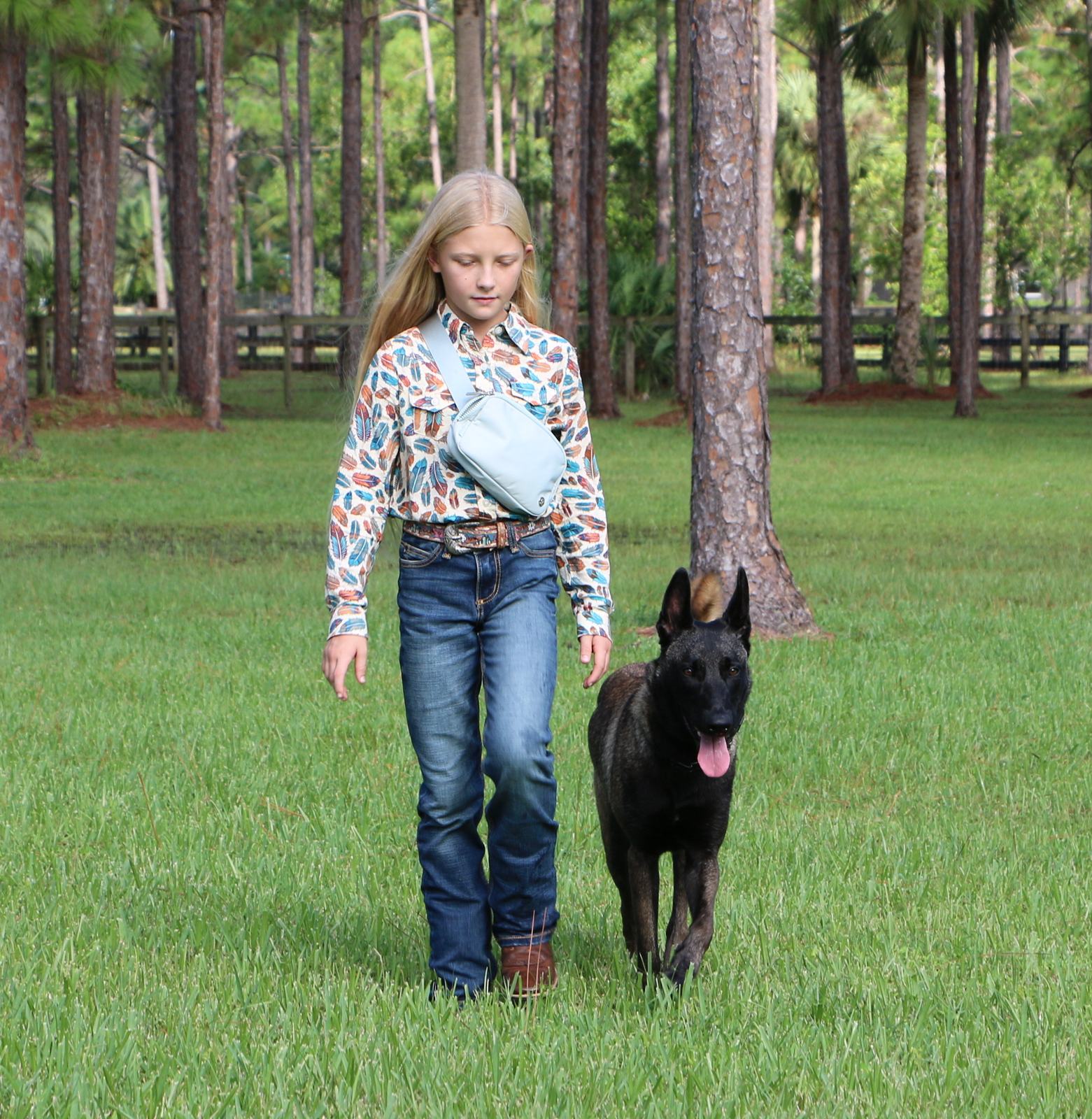 Reese, a Belgian Malinois from American Malinois, with a client’s daughter in a field